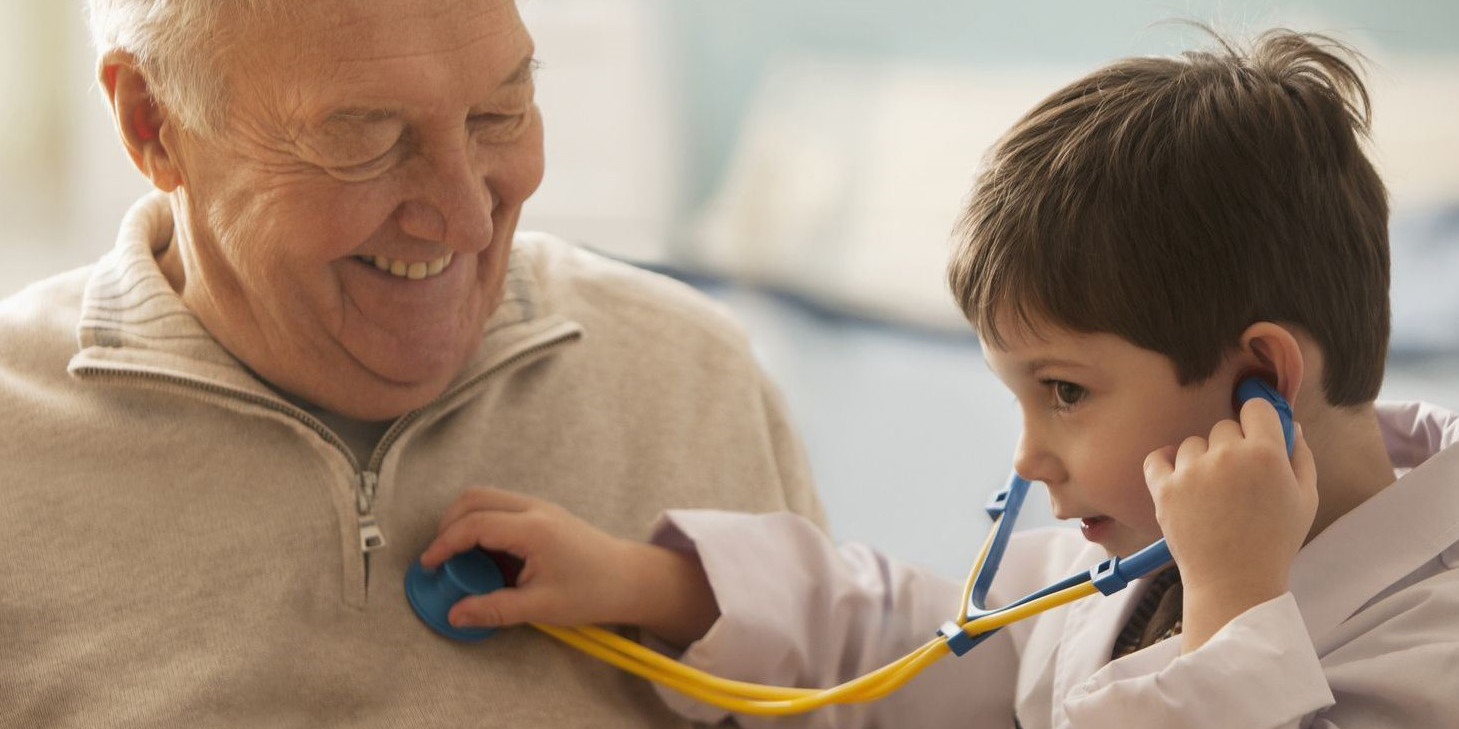 Enkel horcht seinen Opa mit seinem Spielzeug-Stetoskop ab